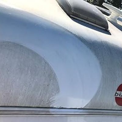 Exterior de una caravana con una parte visiblemente limpiada contrastando con el resto sucio, mostrando el proceso de eliminación de suciedad. Se ve el logotipo de